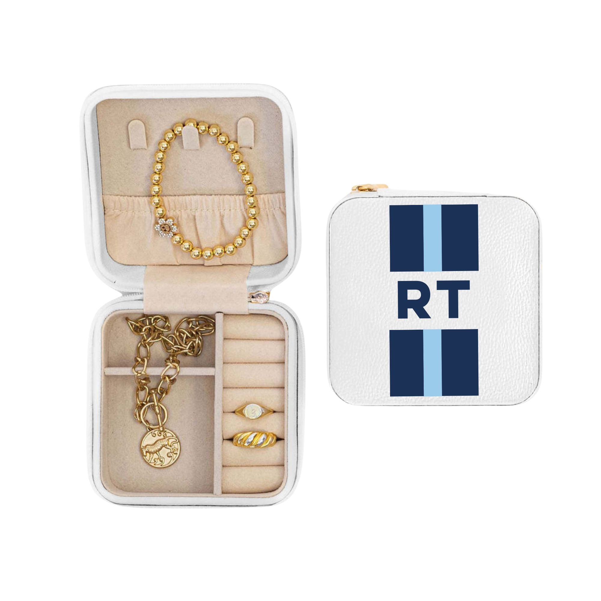 An open jewelry case is filled with jewelry and sits next to a closed case with a blue stripe monogram design.