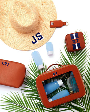 An assortment of personalized tan leather products with navy monograms.