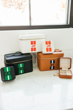 A group of matching train cases and jewelry cases are set on a bathroom counter.