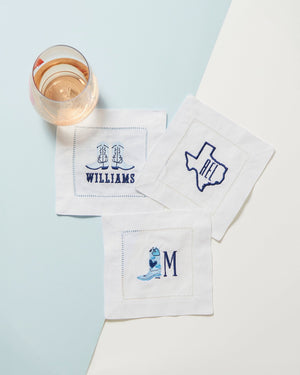 Three customized napkins are paired together with blue embroidered designs.
