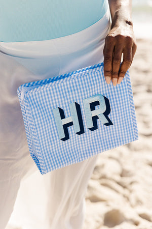 A person holds a blue gingham roadie with a blue block monogram.