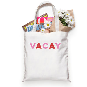 A white cotton tote reads "VACAY" across the front in pink and red letters