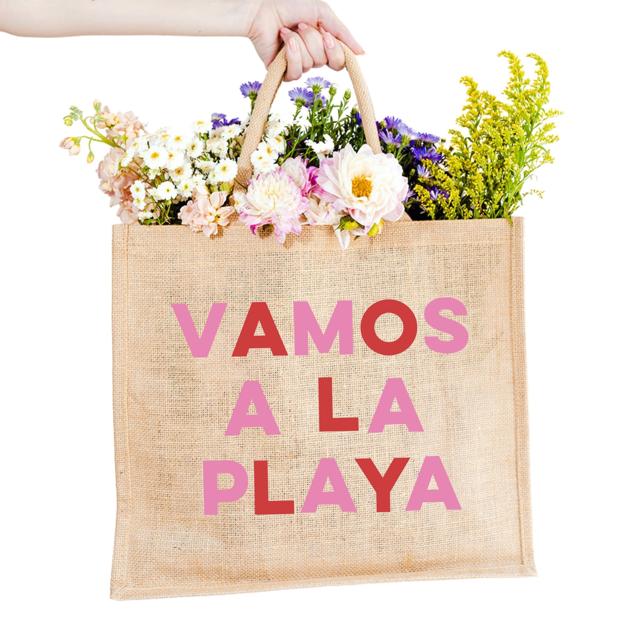 A jute tote reads "VAMOS A LA PLAYA" across the front in red and pink letters