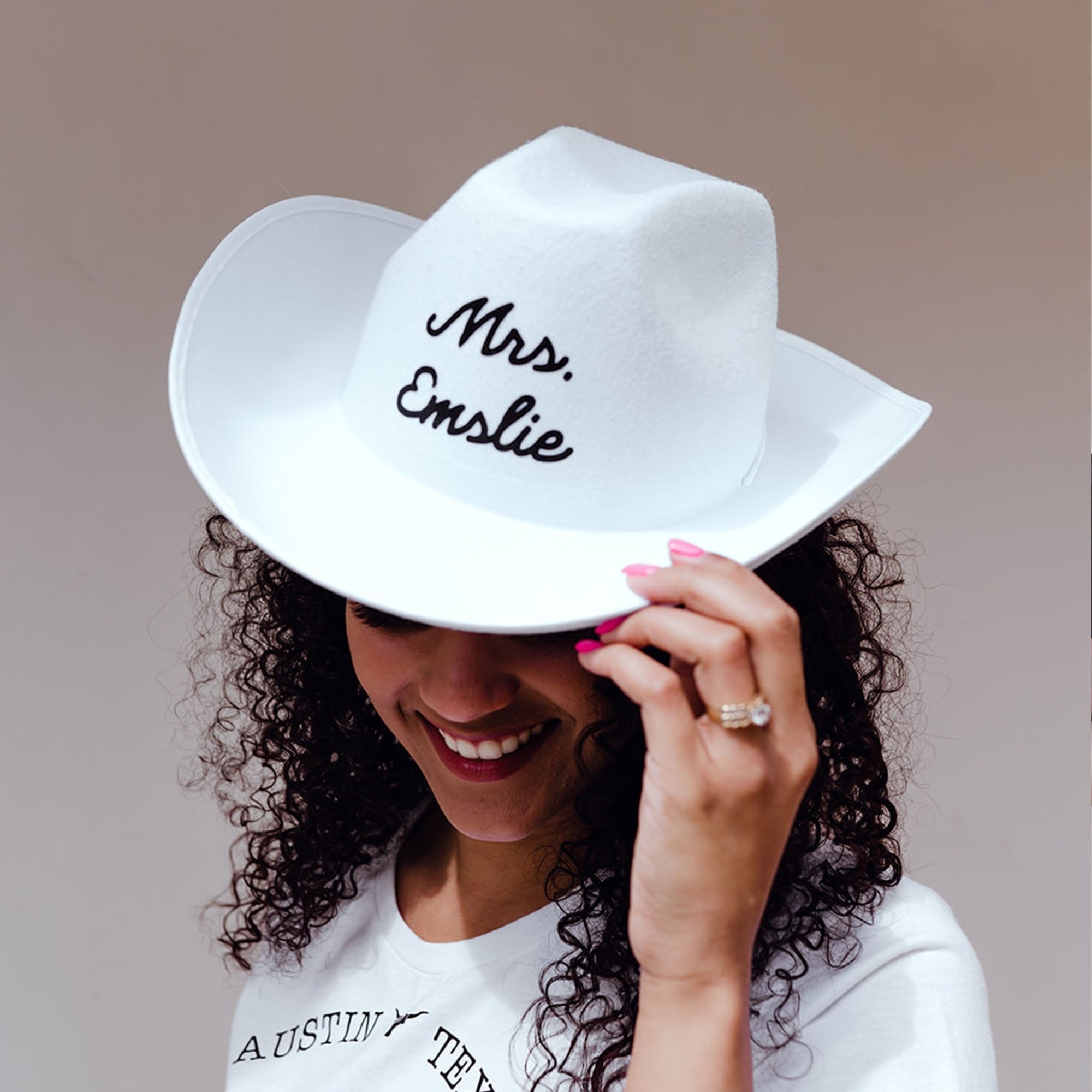 A white cowboy hat is customized with a last name.