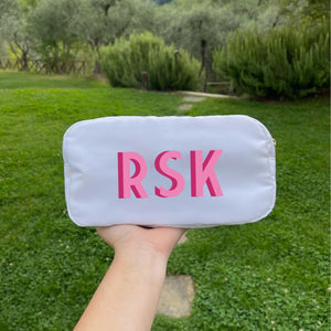 A white nylon pouch is personlized with a pink monogram
