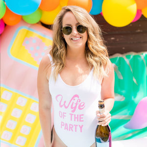 A woman wears a swimsuit that reads "Wife of the Party"