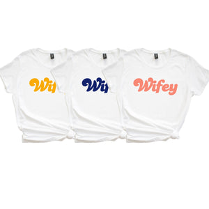 3 white shirts are customized with "Wifey" in different colors.